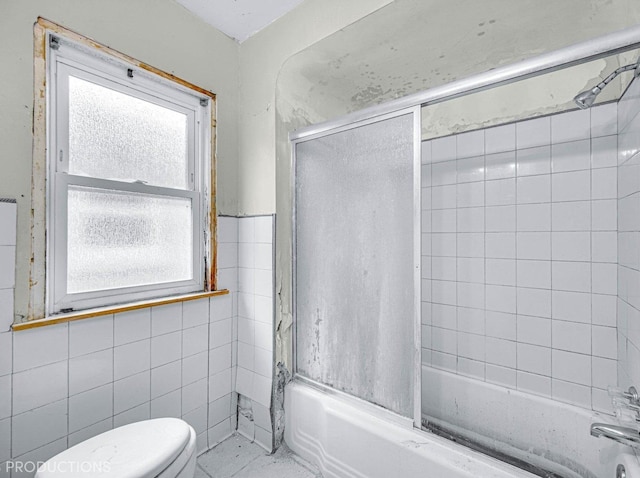 bathroom featuring shower / bath combination with glass door, tile patterned flooring, tile walls, and toilet