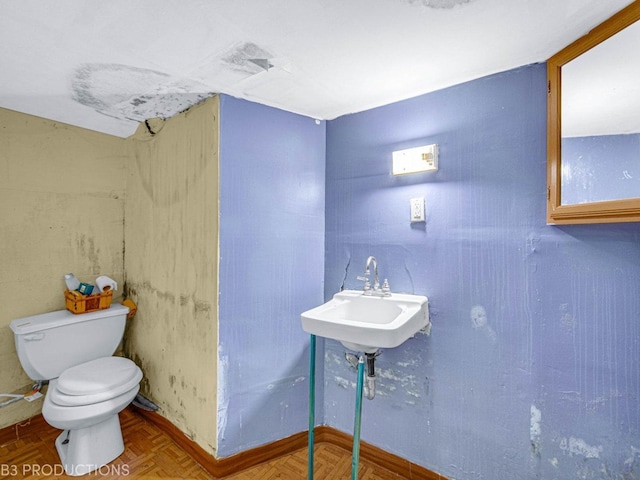 bathroom with sink, toilet, and parquet flooring