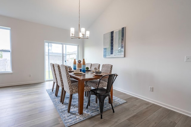 dining room featuring an inviting chandelier, baseboards, vaulted ceiling, and wood finished floors