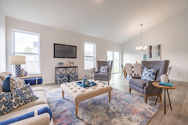 living area featuring a chandelier, lofted ceiling, baseboards, and light wood finished floors