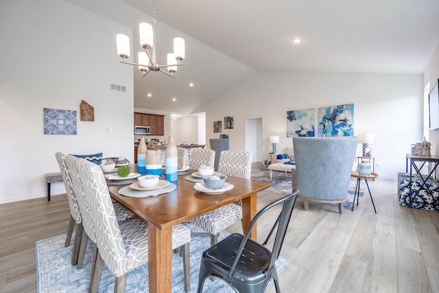 dining area featuring light wood finished floors, baseboards, visible vents, and a notable chandelier