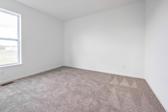 carpeted spare room featuring visible vents and baseboards