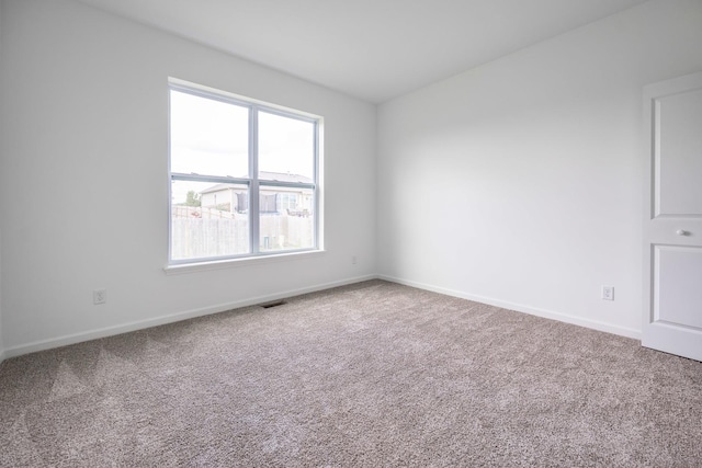 carpeted spare room featuring visible vents and baseboards