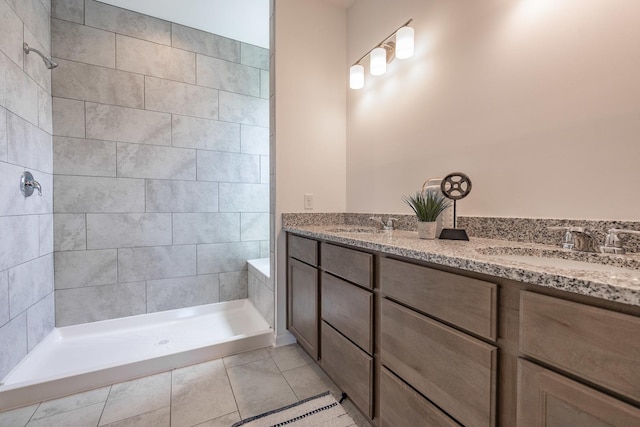 full bath featuring double vanity, a stall shower, a sink, and tile patterned floors