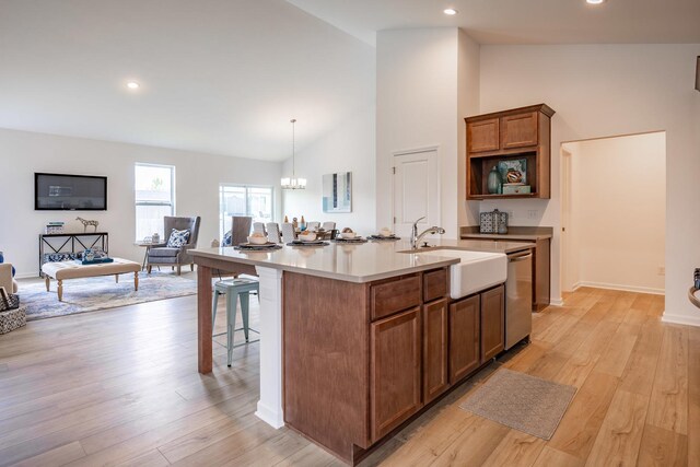 kitchen with decorative light fixtures, light countertops, stainless steel dishwasher, a sink, and an island with sink