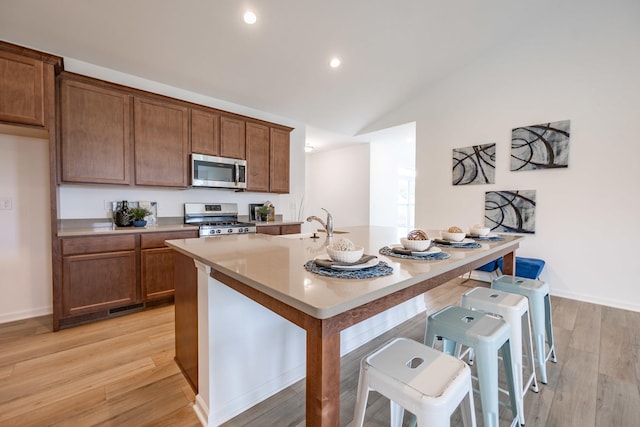 kitchen with appliances with stainless steel finishes, brown cabinets, light countertops, and a kitchen bar