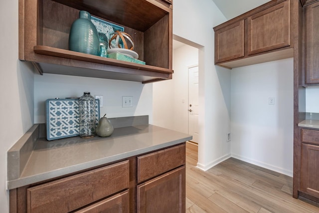 kitchen featuring light wood-style floors, baseboards, open shelves, and light countertops