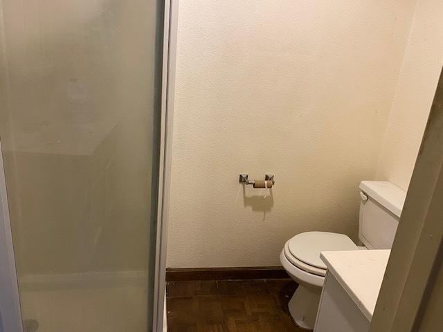 bathroom featuring parquet flooring, vanity, and toilet