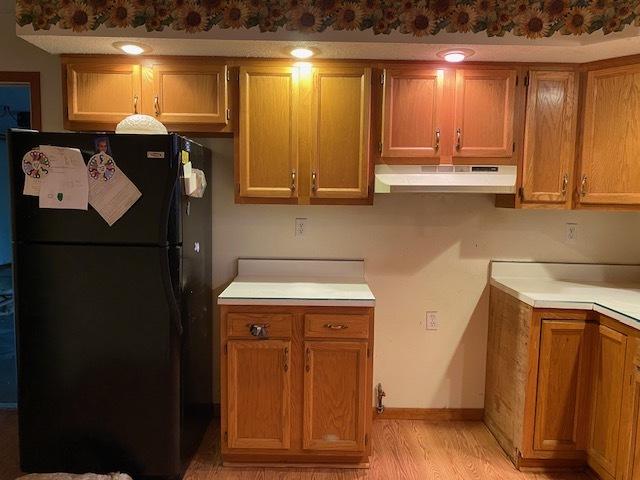 kitchen featuring light wood-type flooring and black fridge