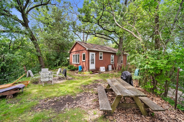 view of yard featuring entry steps, outdoor dining space, and an outdoor structure