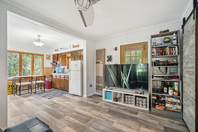 living room with a barn door, ornamental molding, and wood finished floors