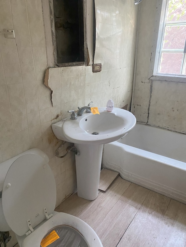 10840 S Buffalo Ave, Chicago, IL 60617 - bathroom with toilet, a bath, tile walls, and wood finished floors
