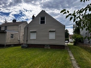 back of house with cooling unit and a lawn