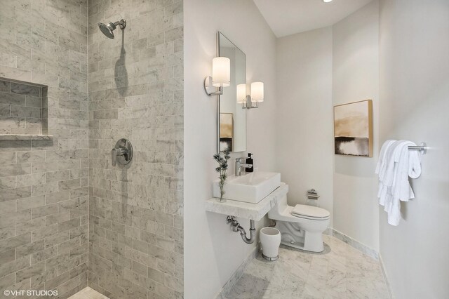 bathroom with sink, tile patterned flooring, a tile shower, and toilet