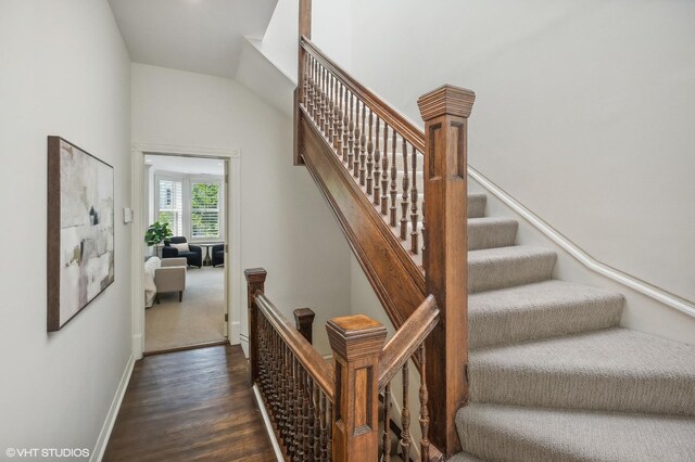 stairway with lofted ceiling and dark wood-type flooring