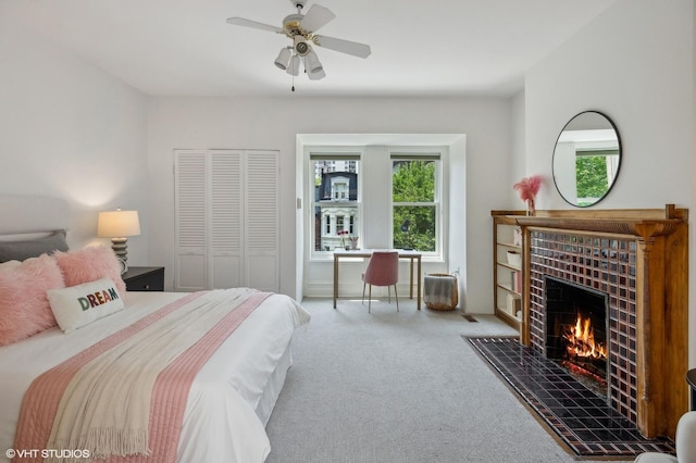 bedroom with multiple windows, a fireplace, ceiling fan, and carpet flooring