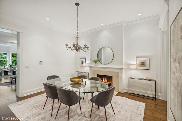 dining space with a premium fireplace, dark wood-type flooring, crown molding, and a notable chandelier