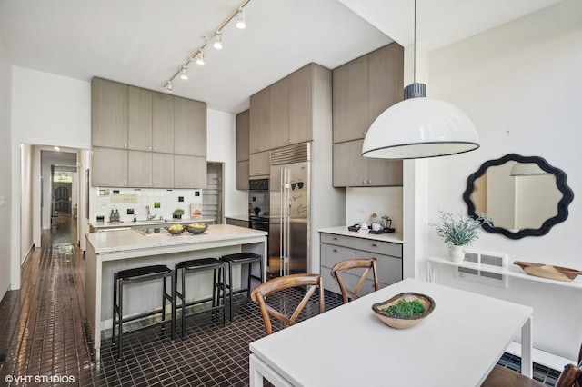 kitchen featuring dark tile patterned floors, sink, decorative backsplash, a center island, and built in refrigerator