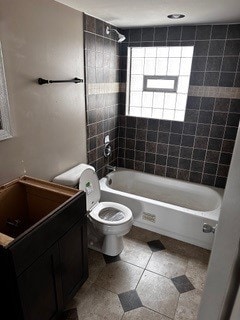 full bathroom featuring vanity, tiled shower / bath combo, toilet, and tile patterned flooring