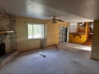 unfurnished living room featuring a brick fireplace, brick wall, a textured ceiling, and light colored carpet