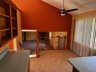 interior space featuring ceiling fan, high vaulted ceiling, and light tile patterned floors