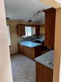 kitchen featuring track lighting, sink, kitchen peninsula, and light tile patterned floors