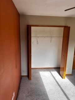 unfurnished bedroom with ceiling fan, light carpet, and a closet