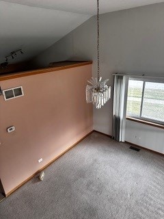 interior space with a notable chandelier, carpet flooring, and rail lighting