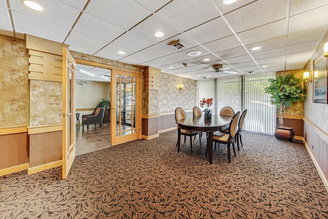 carpeted dining area featuring a paneled ceiling, french doors, and ceiling fan