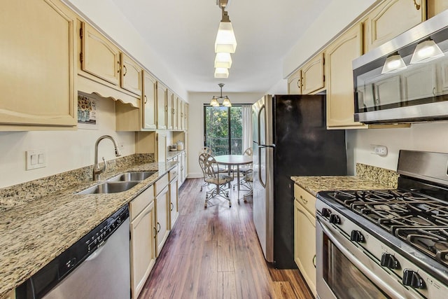 kitchen with appliances with stainless steel finishes, sink, decorative light fixtures, dark hardwood / wood-style floors, and a notable chandelier