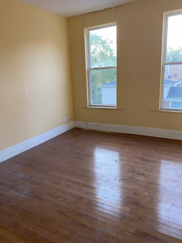 spare room with dark hardwood / wood-style flooring and a healthy amount of sunlight