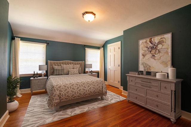 bedroom featuring multiple windows, light hardwood / wood-style flooring, and vaulted ceiling