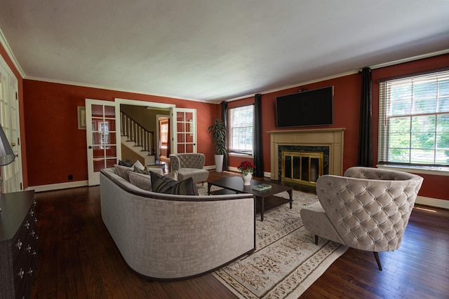 living room featuring crown molding, dark hardwood / wood-style flooring, a high end fireplace, and a healthy amount of sunlight