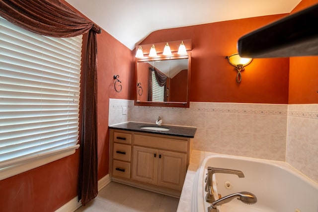 bathroom with tile patterned floors, vanity, a tub, and vaulted ceiling