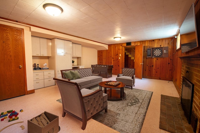 living room featuring a fireplace, crown molding, and wooden walls