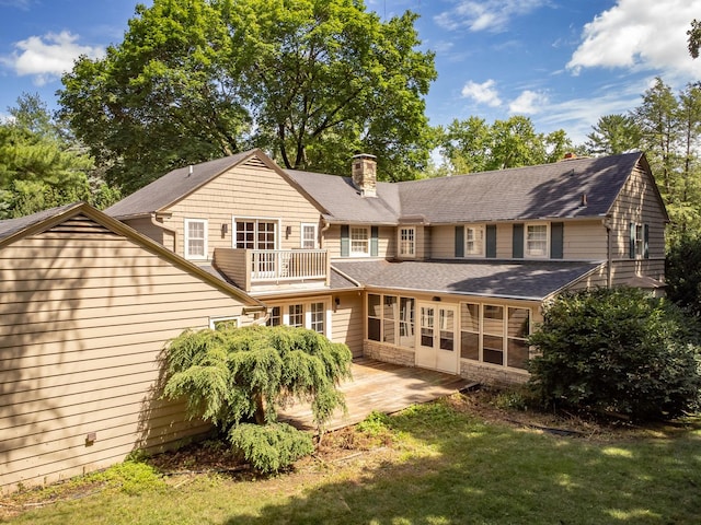 rear view of house with a yard, a balcony, and a patio area