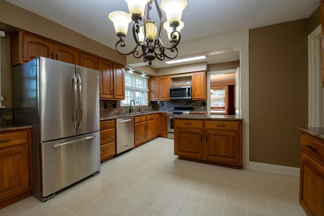 kitchen with appliances with stainless steel finishes, tasteful backsplash, sink, decorative light fixtures, and a chandelier