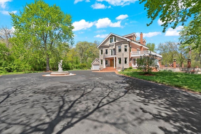 view of front of property with a front yard, a chimney, and a balcony