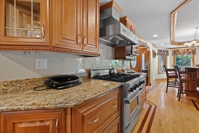 kitchen featuring stainless steel range, tasteful backsplash, brown cabinetry, light stone countertops, and exhaust hood