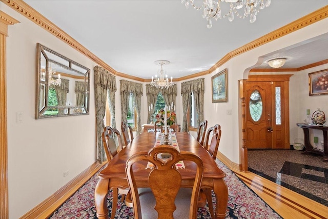 dining room featuring ornamental molding, wood finished floors, baseboards, and an inviting chandelier