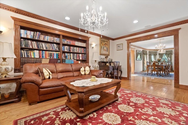 living room featuring baseboards, ornamental molding, wood finished floors, and a notable chandelier