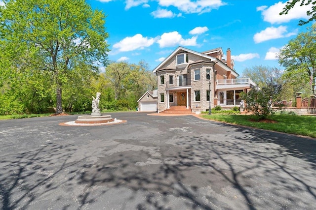 view of front of home with a balcony, a garage, and a chimney