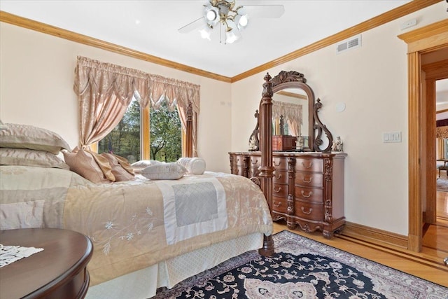 bedroom with crown molding, visible vents, a ceiling fan, wood finished floors, and baseboards