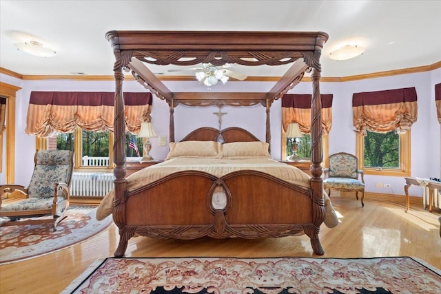 bedroom featuring ornamental molding, multiple windows, baseboards, and wood finished floors