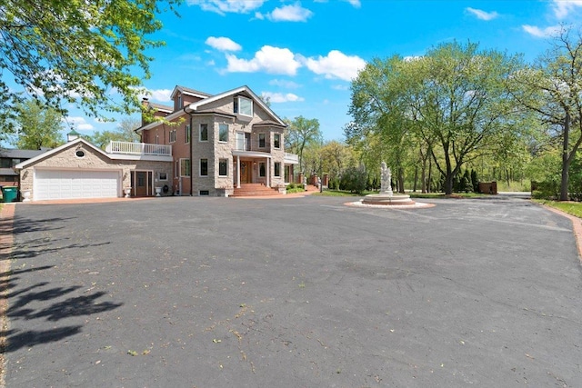 view of front of property with a balcony, a garage, a chimney, and aphalt driveway