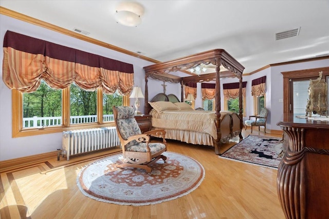 bedroom featuring visible vents, crown molding, radiator heating unit, and wood finished floors