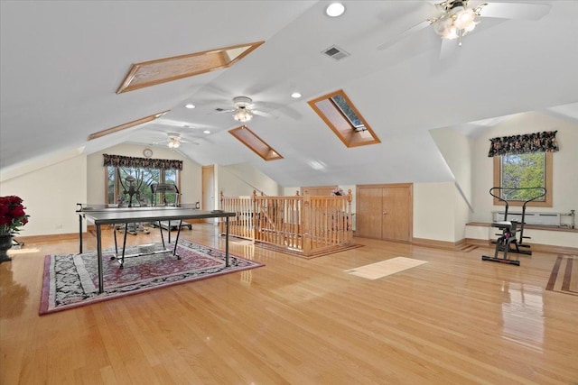 recreation room with baseboards, lofted ceiling with skylight, visible vents, and light wood-style floors