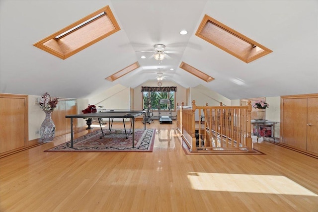 interior space with lofted ceiling with skylight, a ceiling fan, and wood finished floors