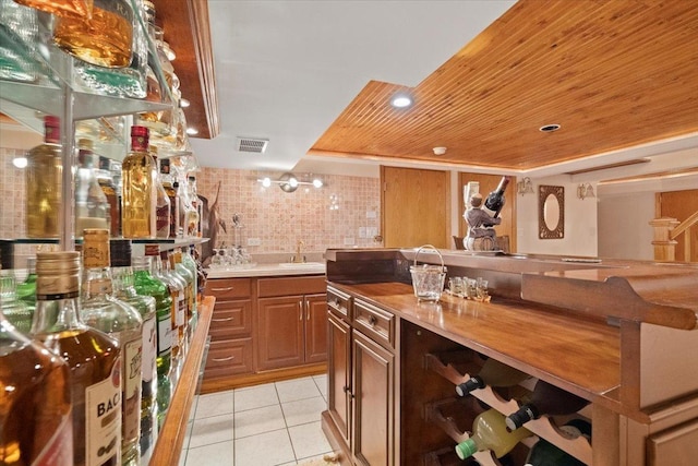 bar featuring light tile patterned floors, wood ceiling, visible vents, and a sink