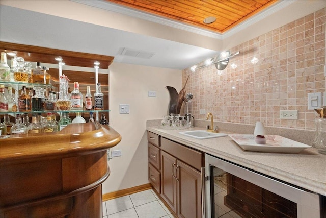 bar featuring indoor wet bar, crown molding, light tile patterned floors, a sink, and beverage cooler